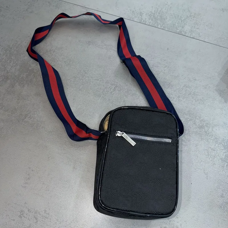 Bag Gucci pequena preta, padrão GG, alça azul e vermelha